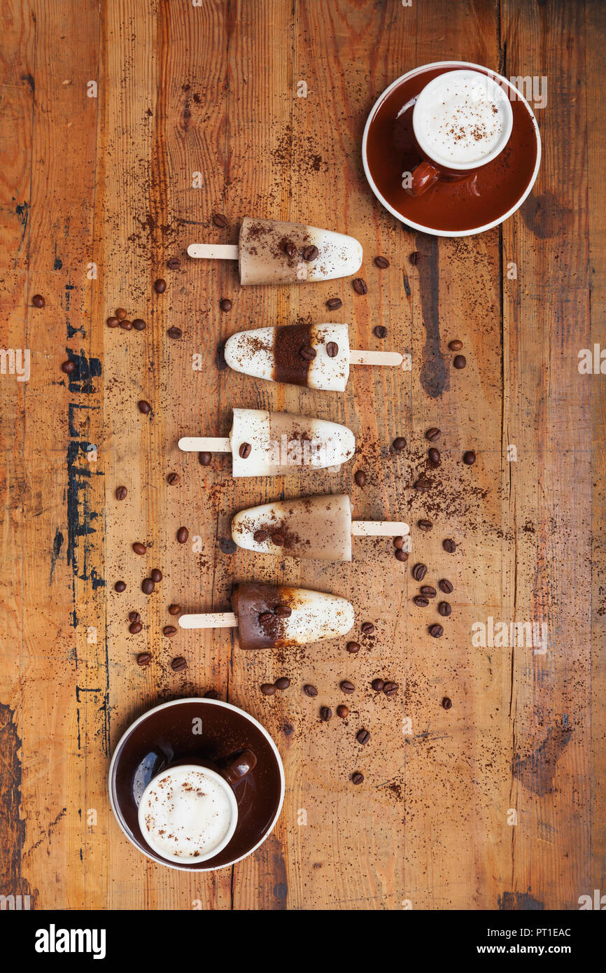 Homemade Espresso Macchiato and Latte Macchiato ice lollies with coffee beans on wooden