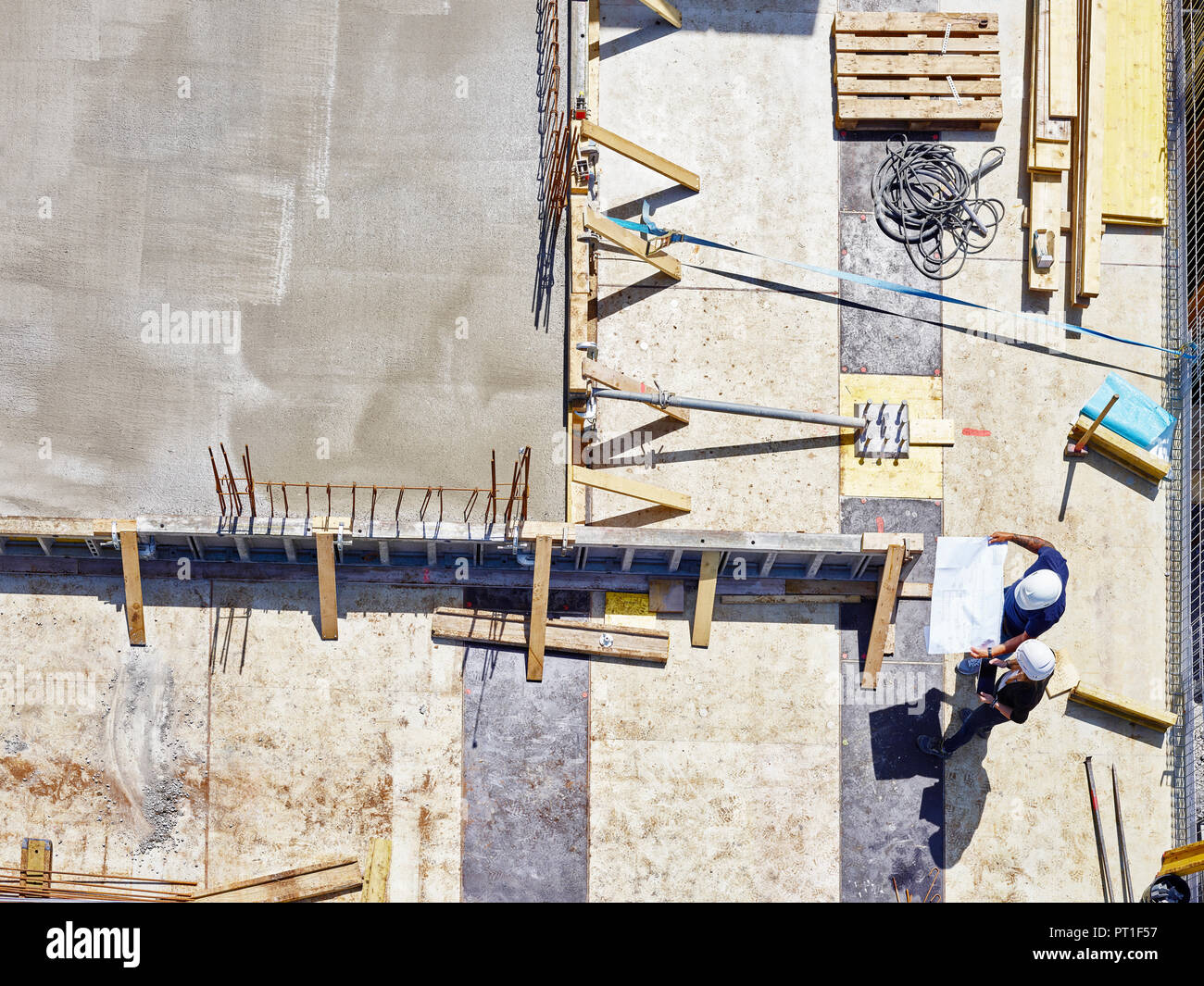 Worker and architect looking at blueprint on construction site Stock Photo