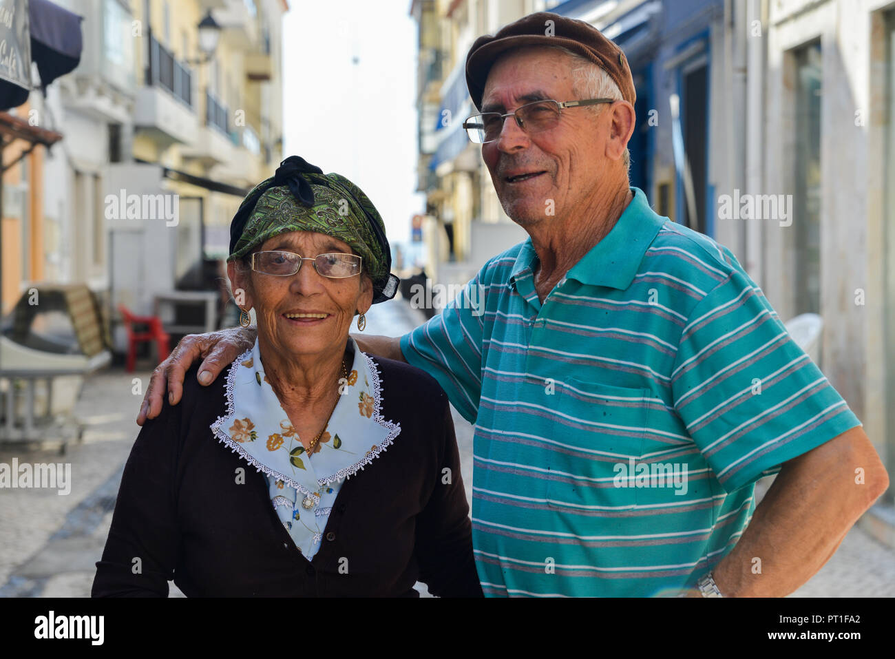Nazare, Portugal - Sept 25, 2018: Traditionally dressed elderly Portuguese woman and her husband on a cobblestone street of Nazare, Portugal Stock Photo