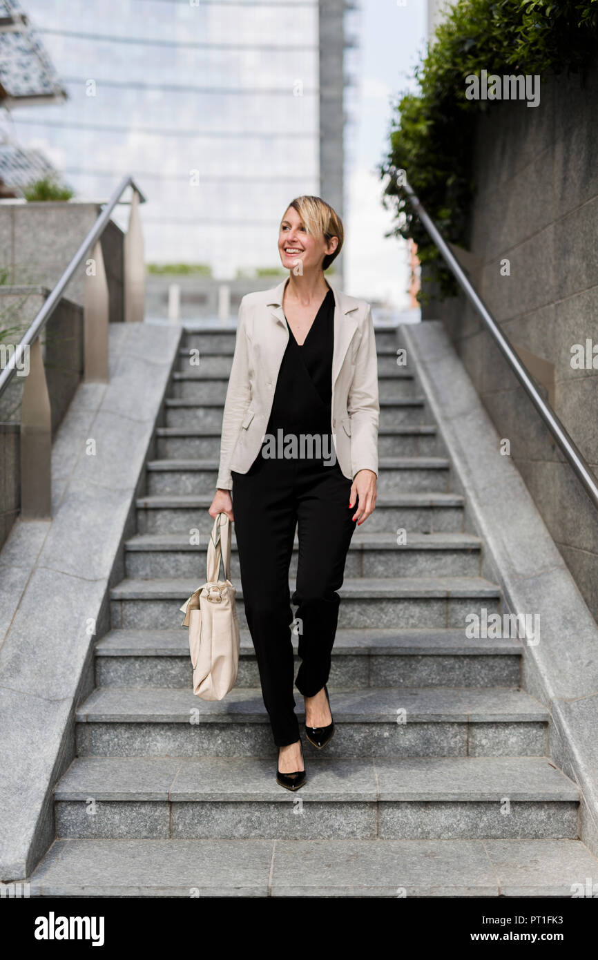 Smiling businesswoman walking downstairs Stock Photo