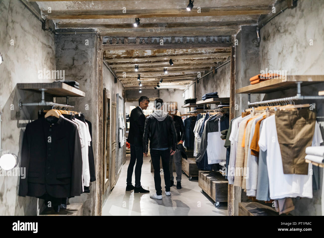Three men standing in modern menswear shop Stock Photo Alamy