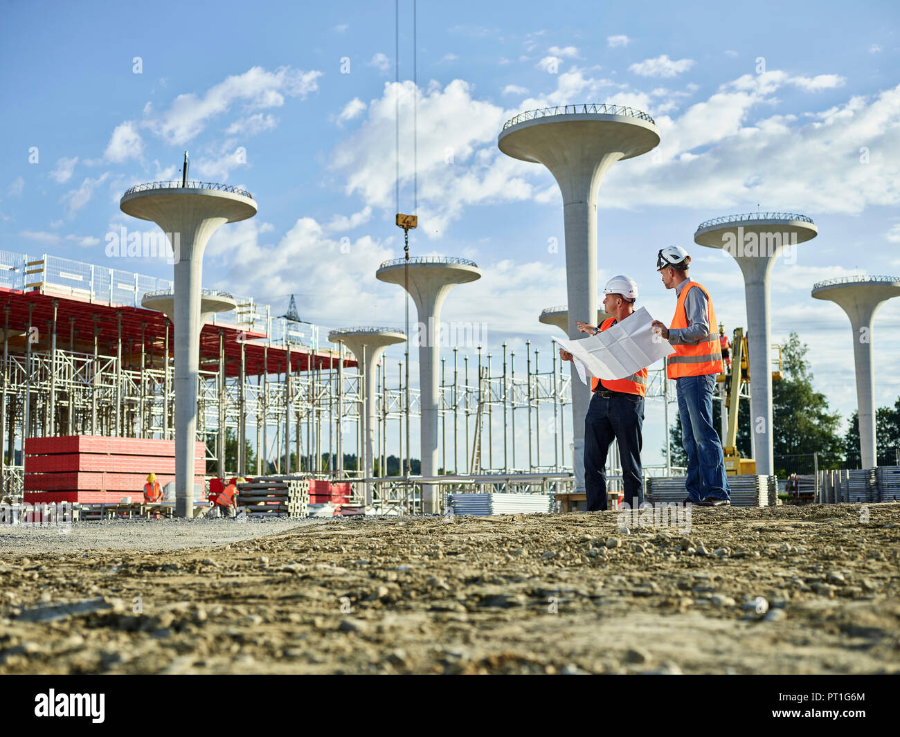 Workers on construction site looking at blueprint with the architect Stock Photo