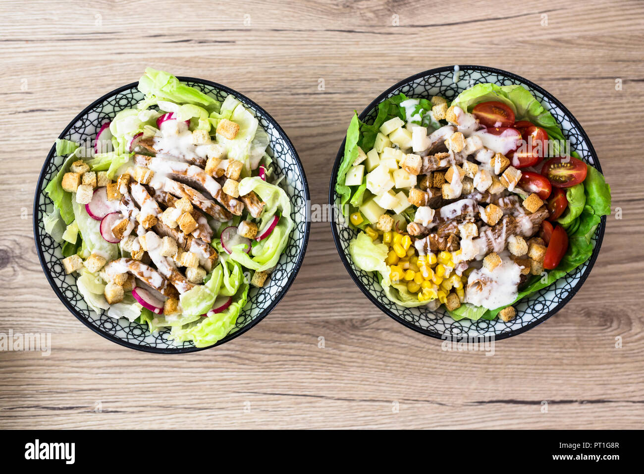 Two bowls of various Caesar salads with meat Stock Photo
