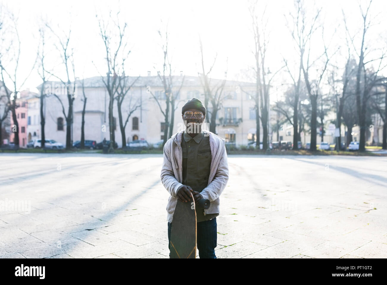 Young amn with skateboard on urban square Stock Photo