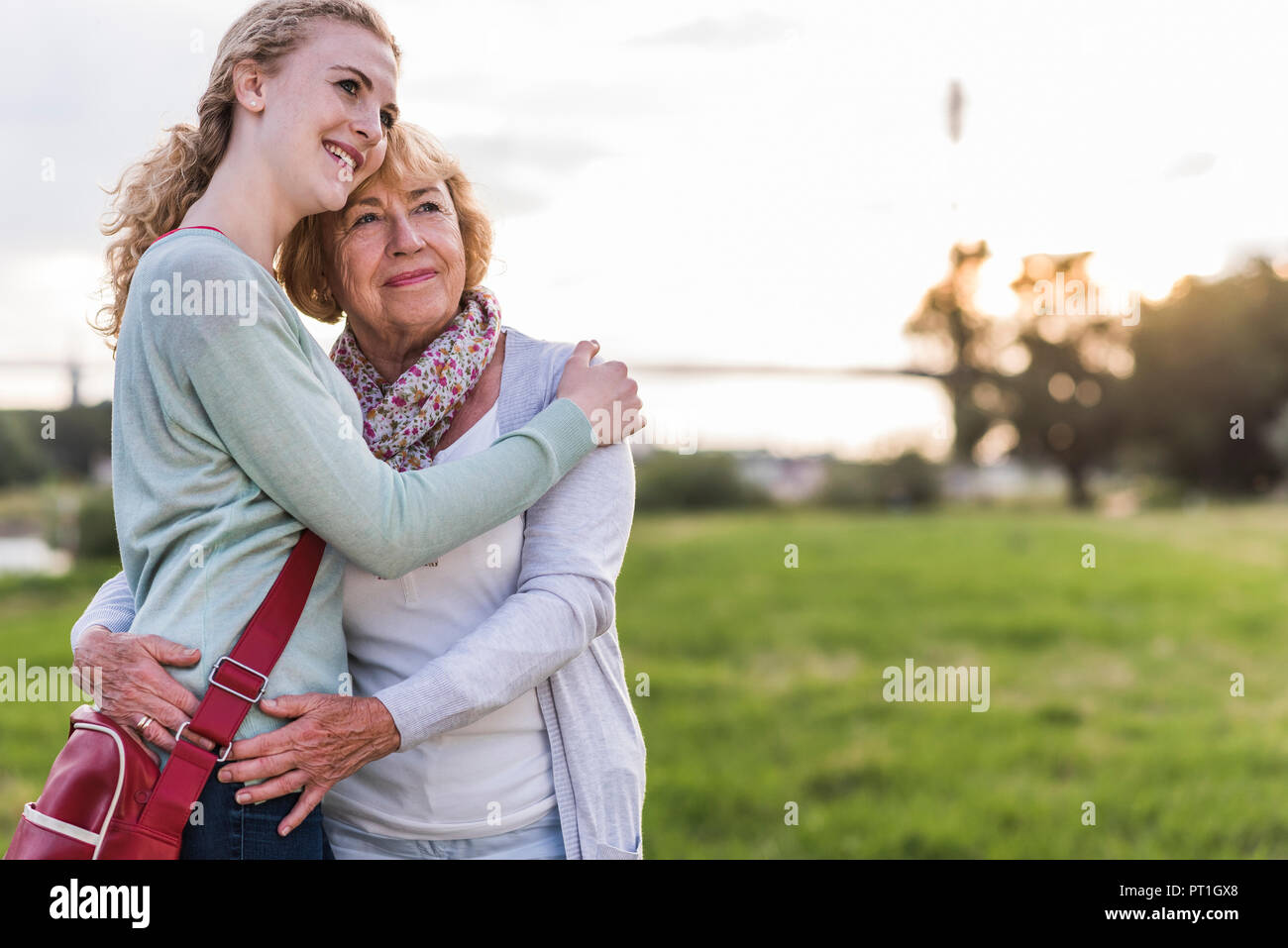 Happy grandmother and granddaughter standing head to head on a meadow Stock Photo