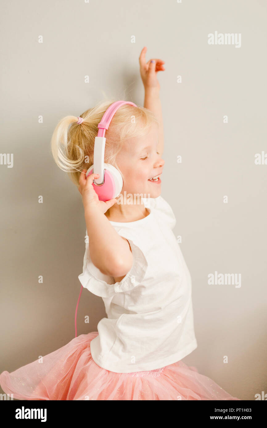 Dancing little girl listening music with headphones Stock Photo