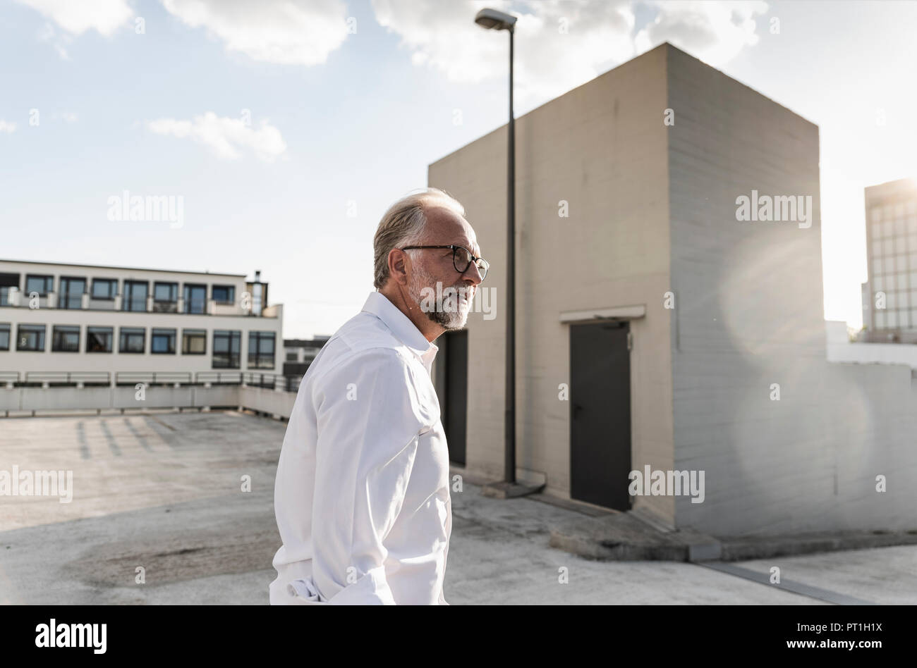 Mature man standing on roof of a high-rise building Stock Photo