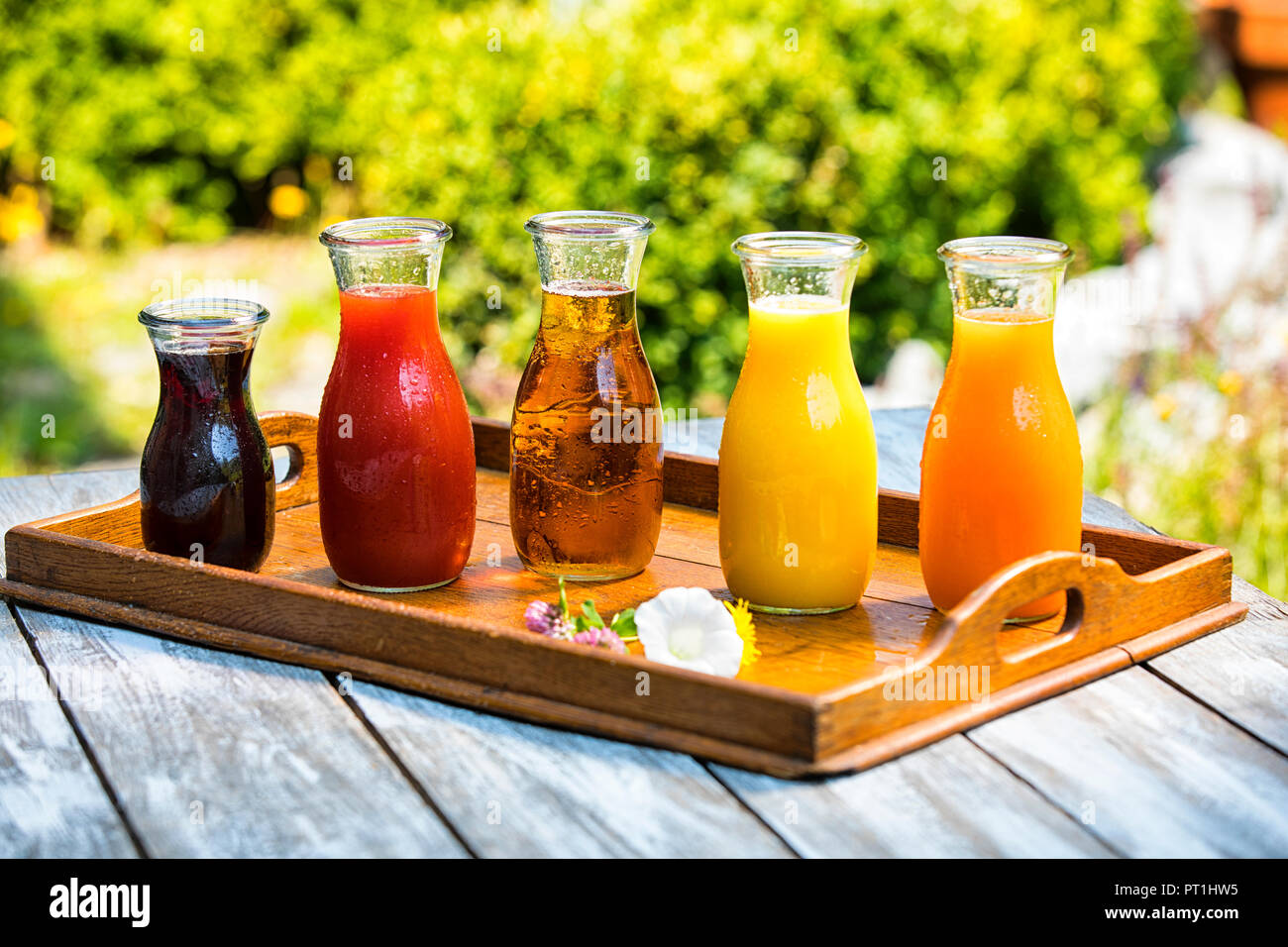 Glass bottles of various fruit juices on wooden tray Stock Photo
