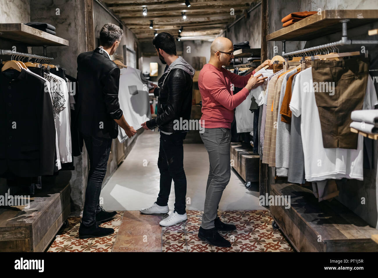 Three men in modern menswear shop with new collection Stock Photo Alamy