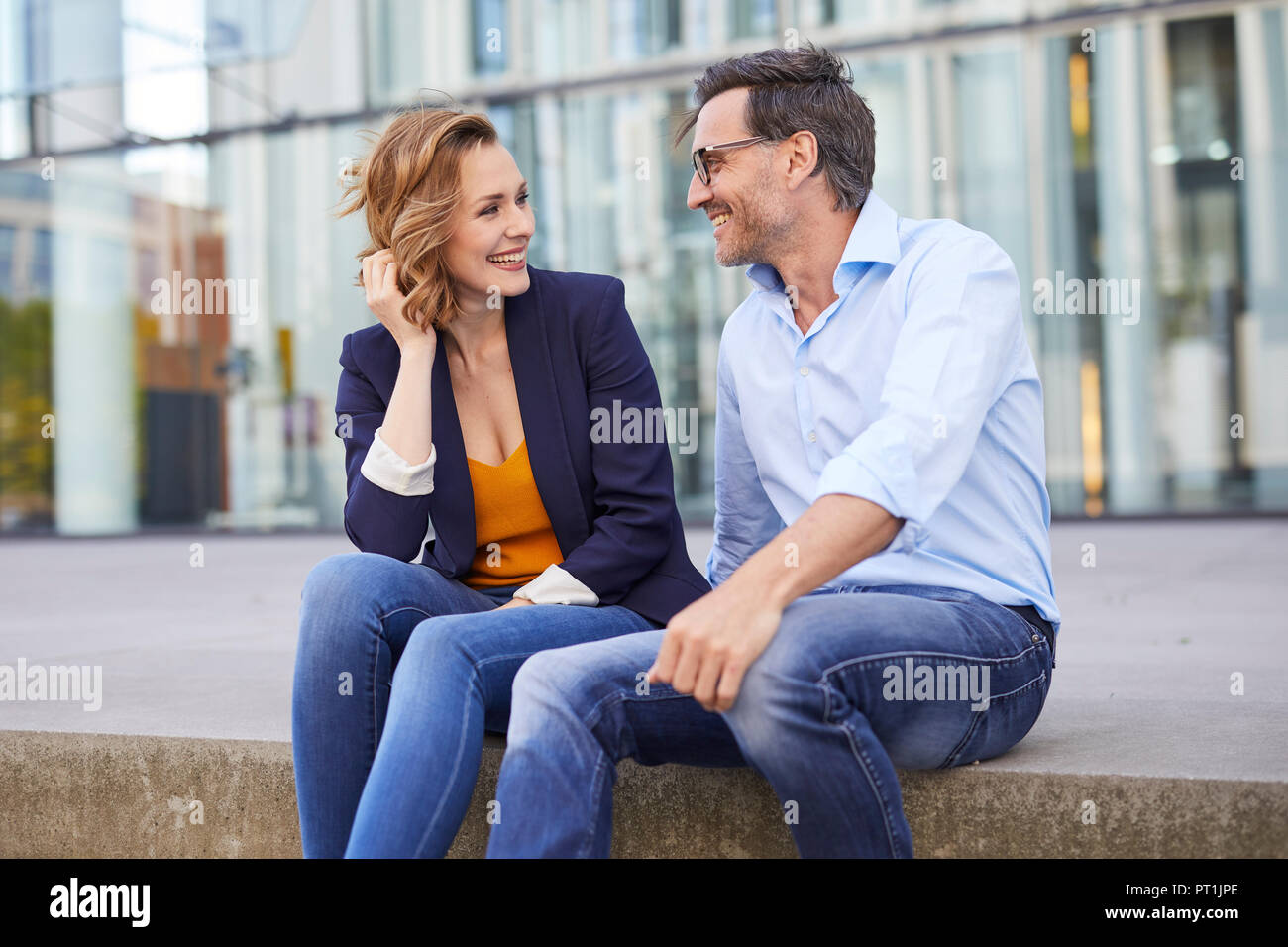 Two business people sitting outdoors talking Stock Photo
