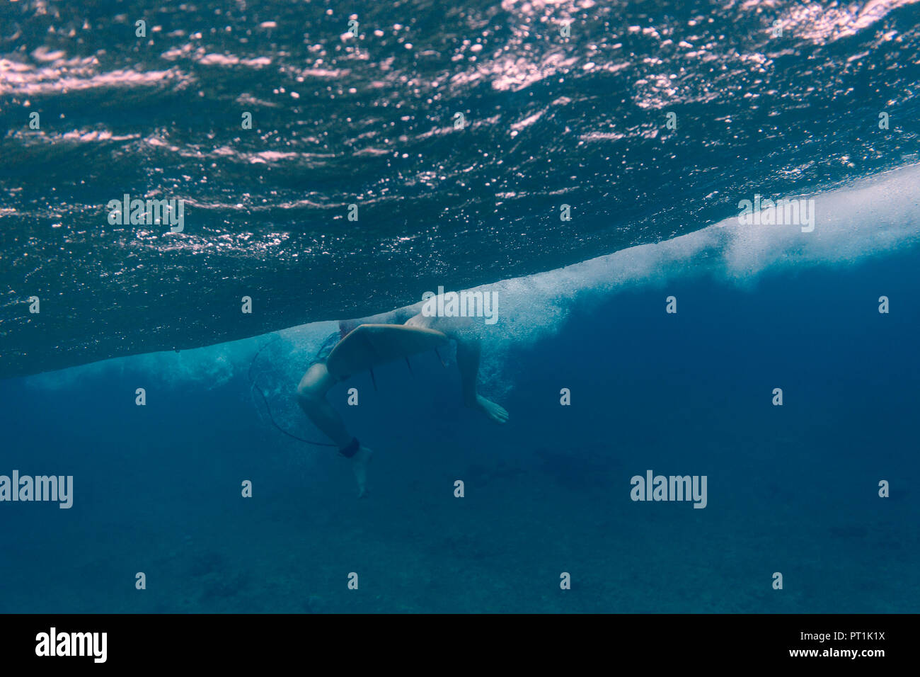Maledives, Indian Ocean, surfer sitting on surfboard, underwater shot