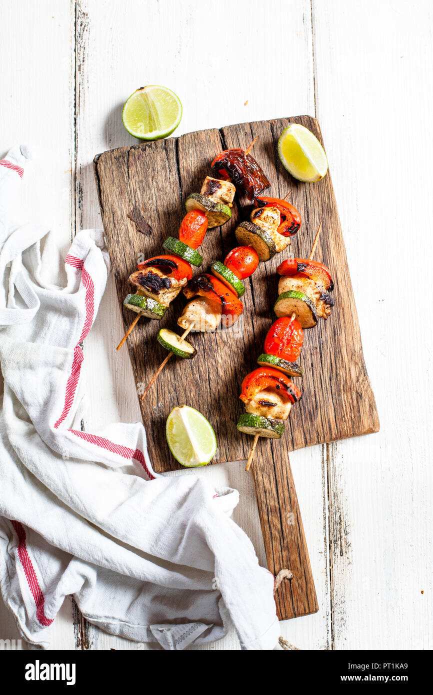 Grill skewers with grilled chicken, tomato, bell pepper and zucchini on chopping board Stock Photo