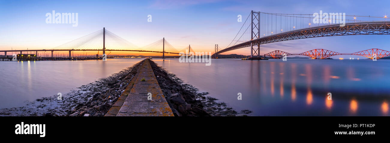 UK, Scotland, Fife, Edinburgh, Firth of Forth estuary, Panorama view from South Queensferry of Forth Bridge, Forth Road Bridge and Queensferry Crossing Bridge at sunset Stock Photo