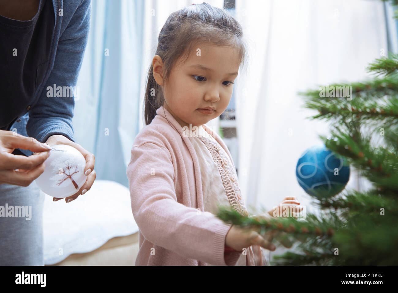 Portrait of little girl decorating Christmas tree with her mother Stock ...