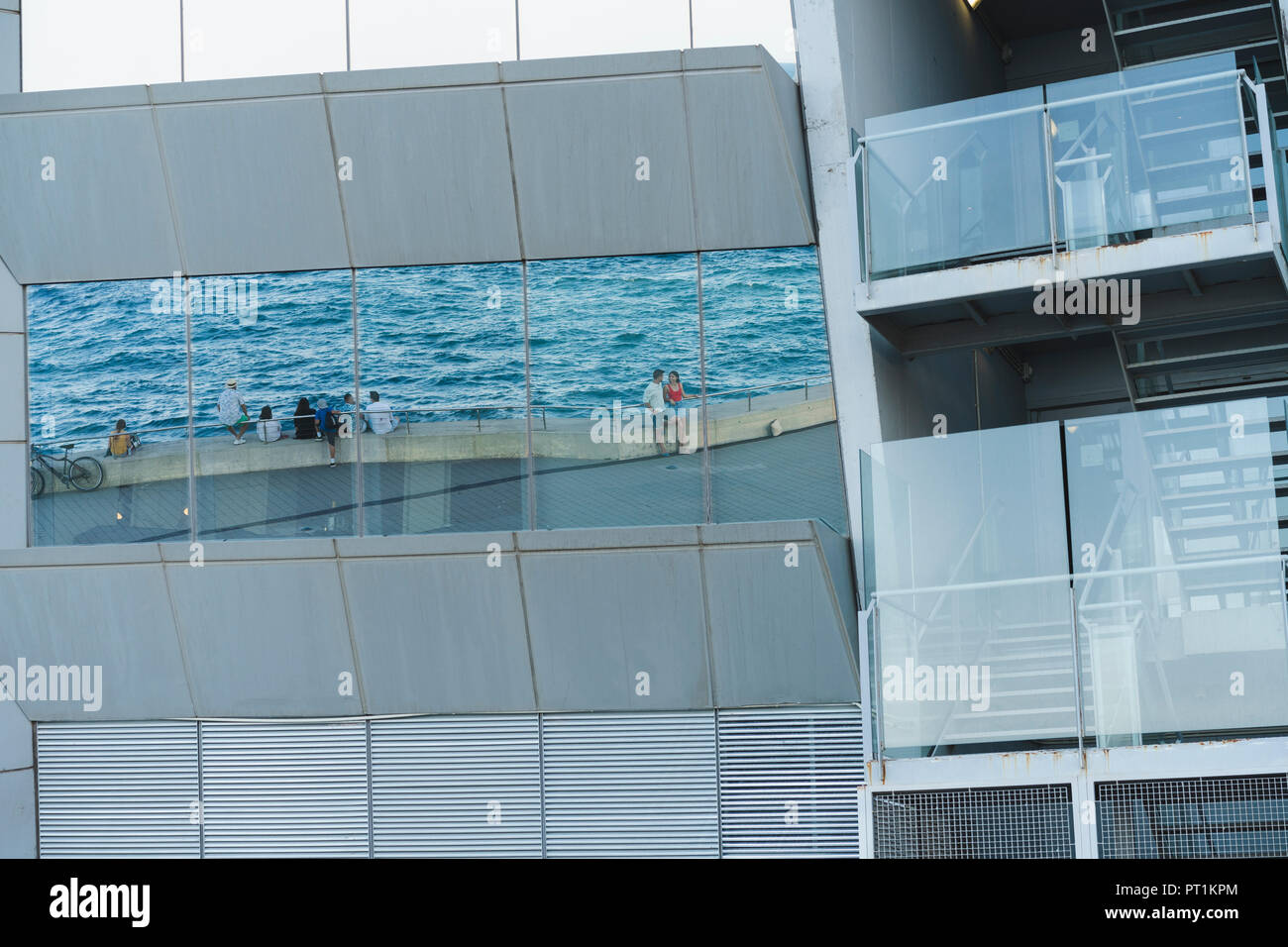 People at the sea, reflection in window of a building Stock Photo