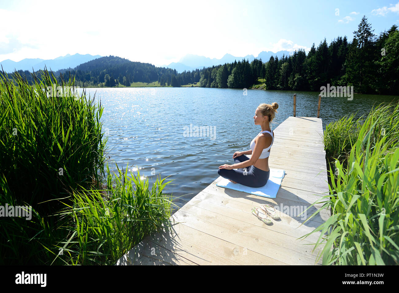 Germany, Mittenwald, woman practising yoga on jetty at lake Stock Photo