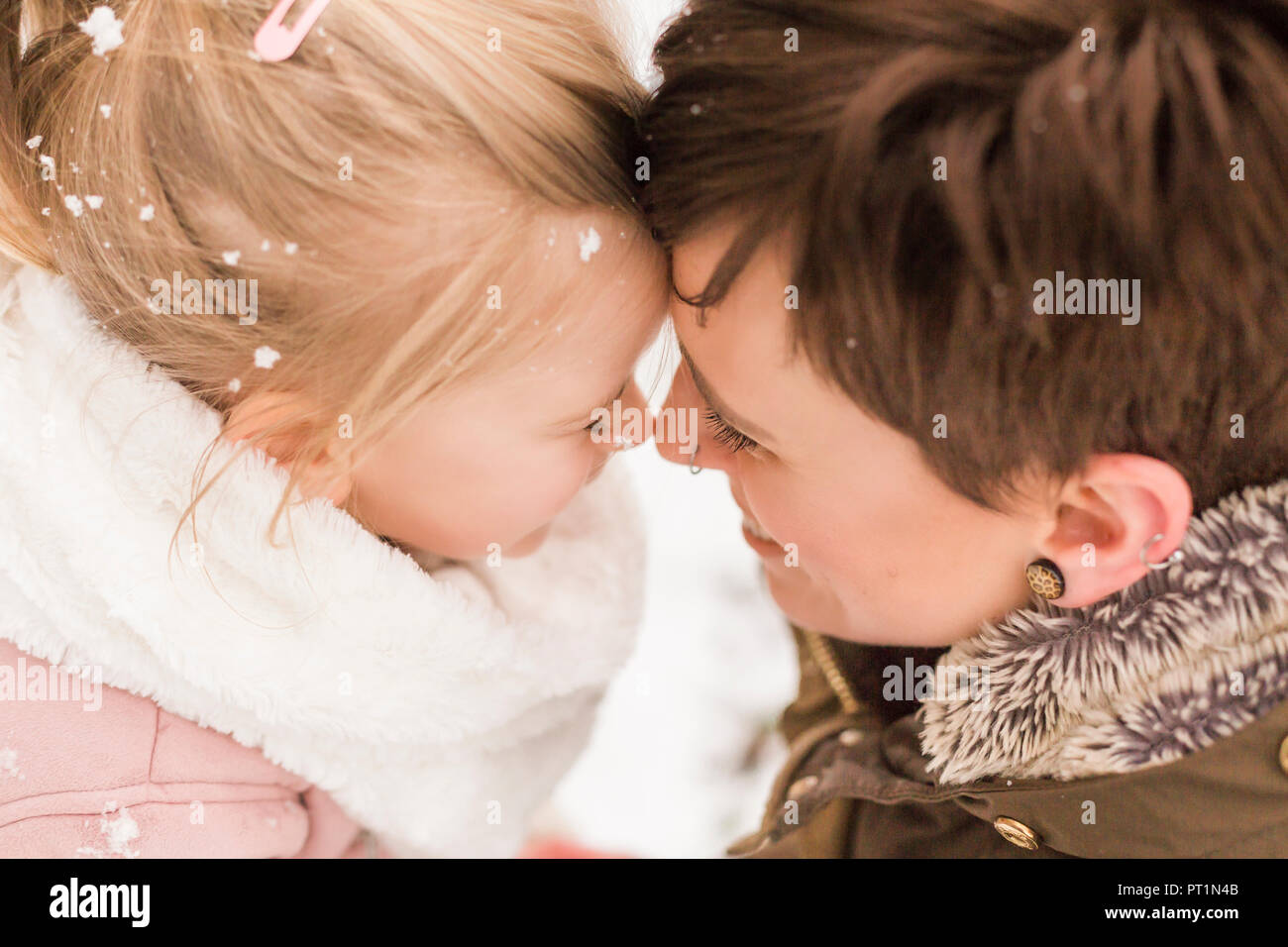 Little girl snuggling with her mother in the snow Stock Photo