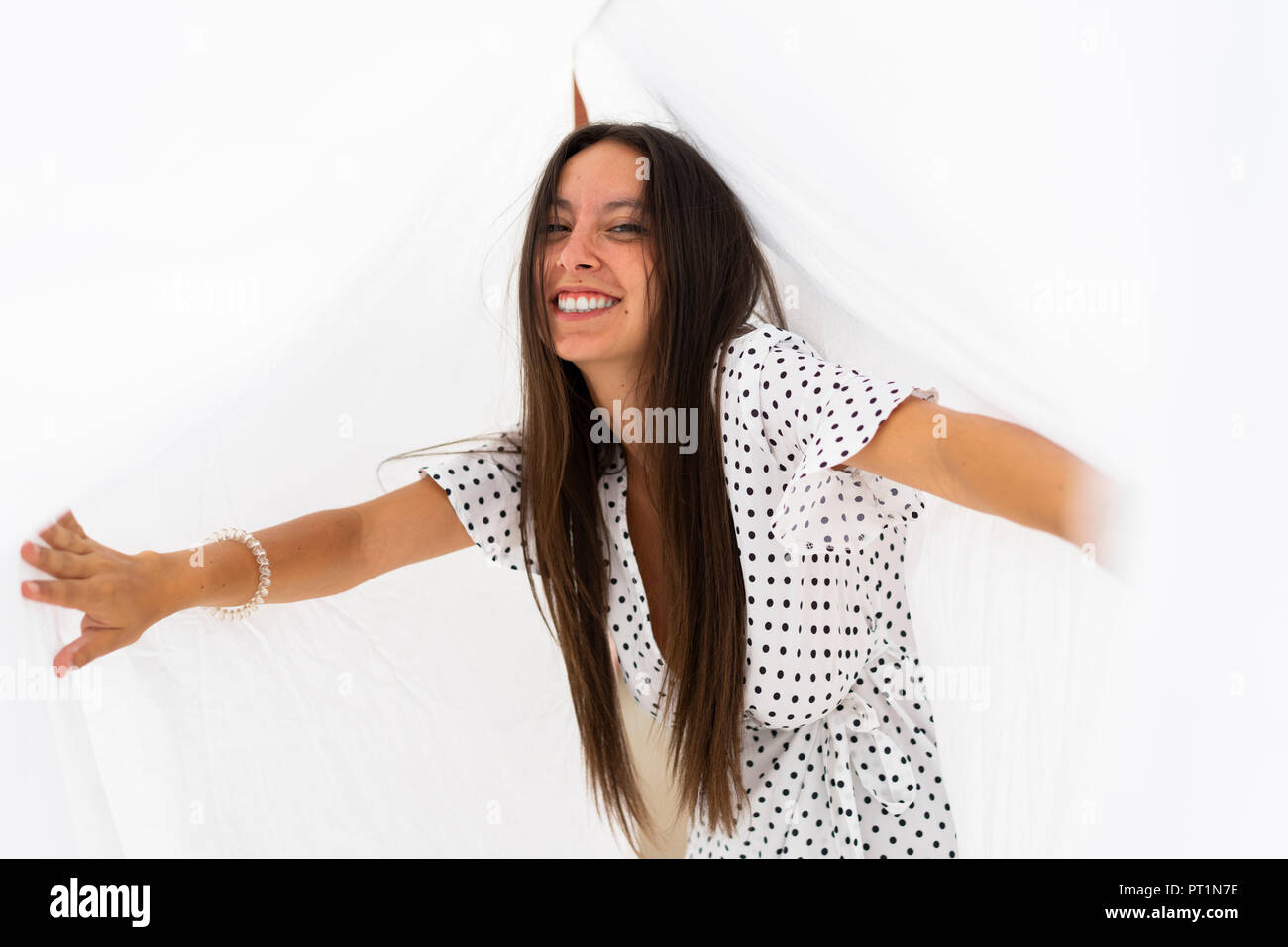 Portrait of young woman having fun with drying bed sheets on roof terrace Stock Photo