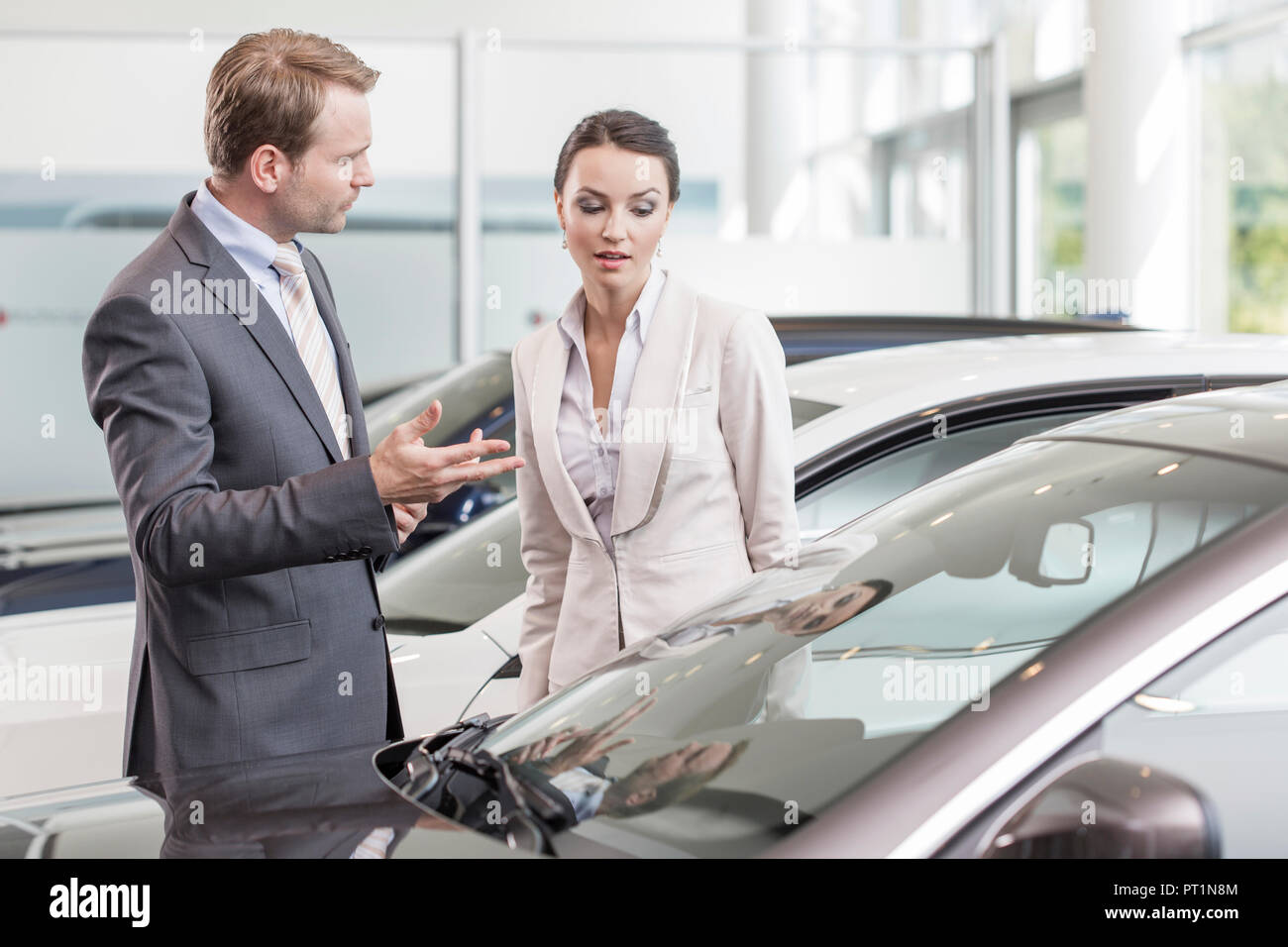 At the car dealer, Salesman showing new car to client Stock Photo