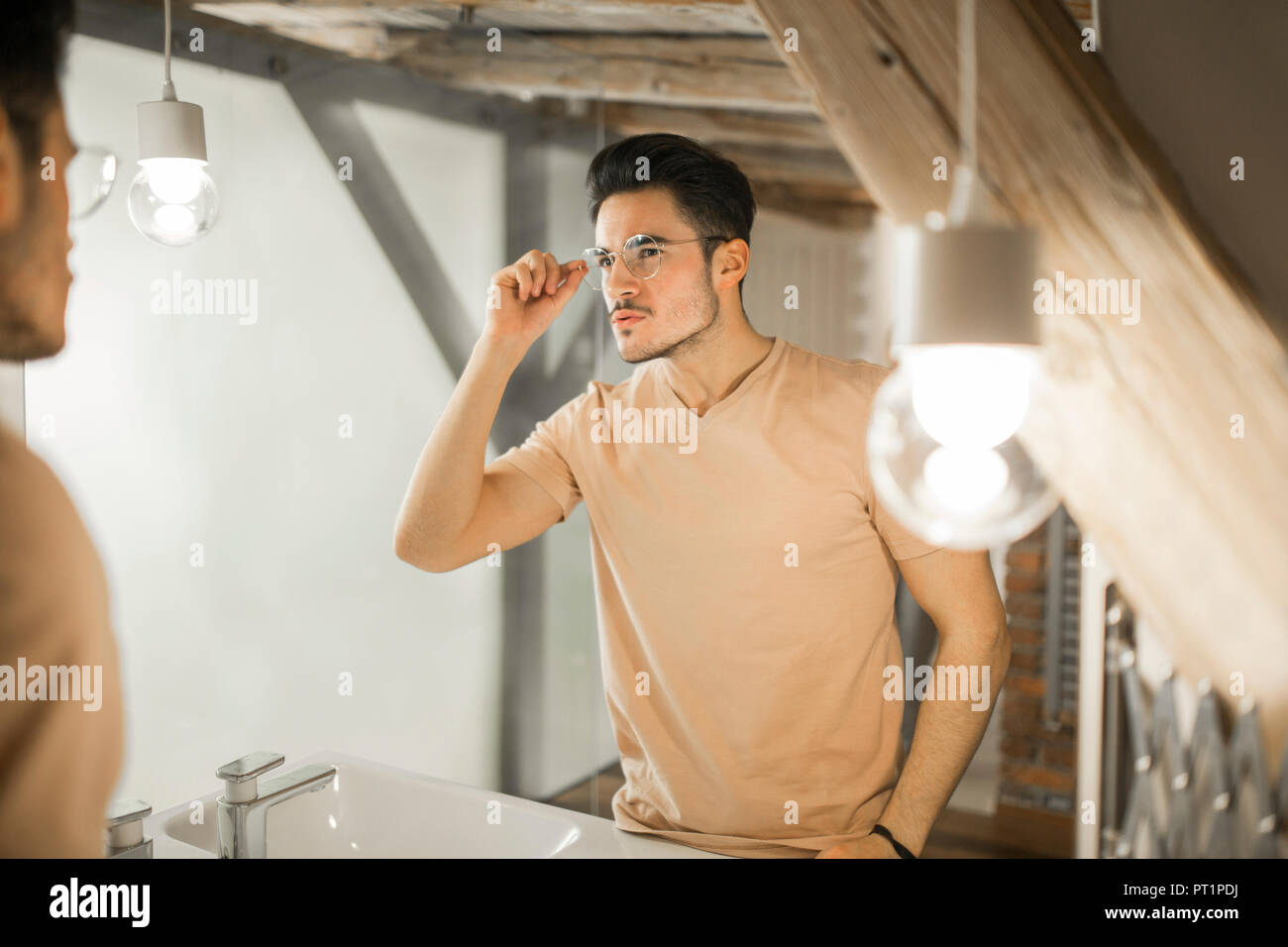 Young man looking in bathroom mirror Stock Photo