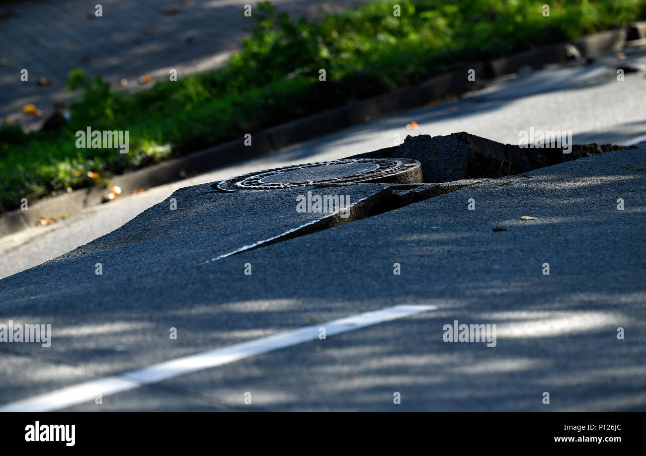 06 October 2018, North Rhine-Westphalia, Dortmund: A manhole cover can be seen along the sunken Emscherallee in the Huckarde district. The road continued to sag yesterday for several meters and is now closed for 150 meters. A large detour has been set up. Photo: Ina Fassbender/dpa Stock Photo