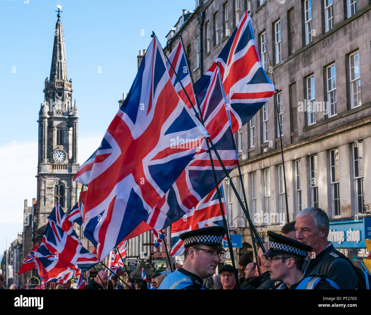 Holyrood, Edinburgh, Scotland, United Kingdom, 6th October 2018. All Under One Banner (AUOB) Scottish March and Rally for Independence, with supporters walking down the Royal Mile to Holyrood Park for a rally. AOUB is a pro-independence campaign for whose core aim is to march at regular intervals until Scotland achieves independence. Pro Union supporters on the Royal Mile wave Union Jacks with Tron Kirk spire in background Stock Photo