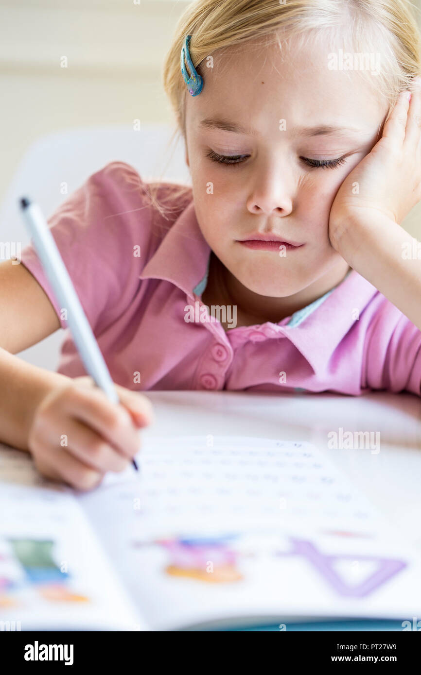Portrait of bored little girl writing numbers in exercise book Stock Photo