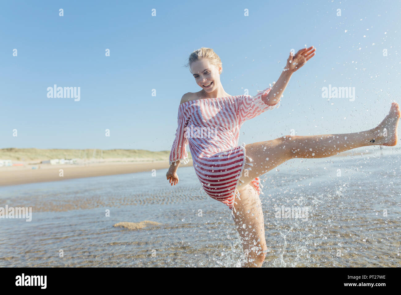 Netherlands, young woman splashing water at the beach in summer Stock ...