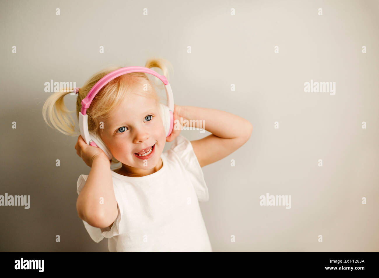Portrait of little girl listening music with headphones dancing Stock Photo