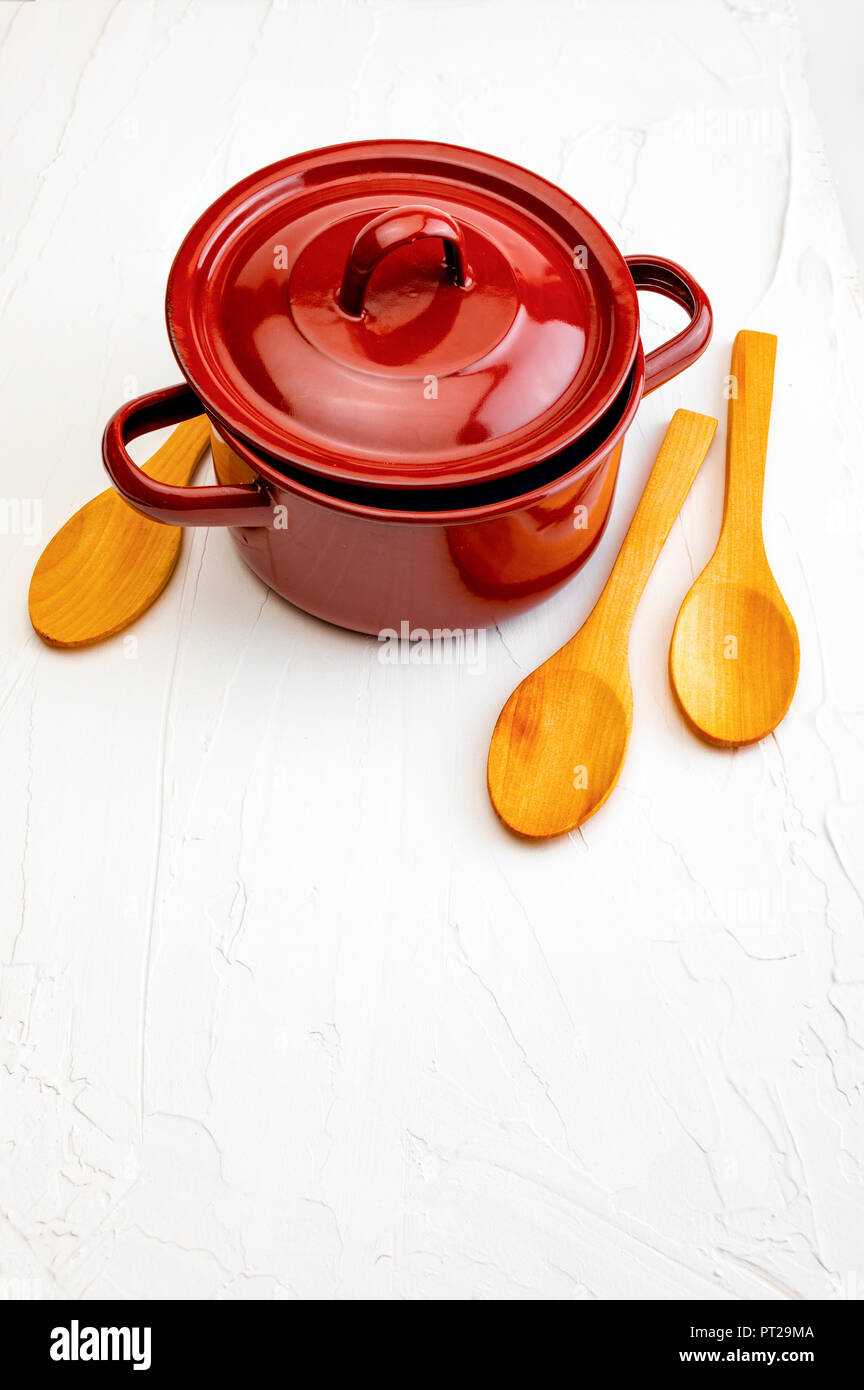 Casserole and wooden spoons on white background with texture. Space to ...