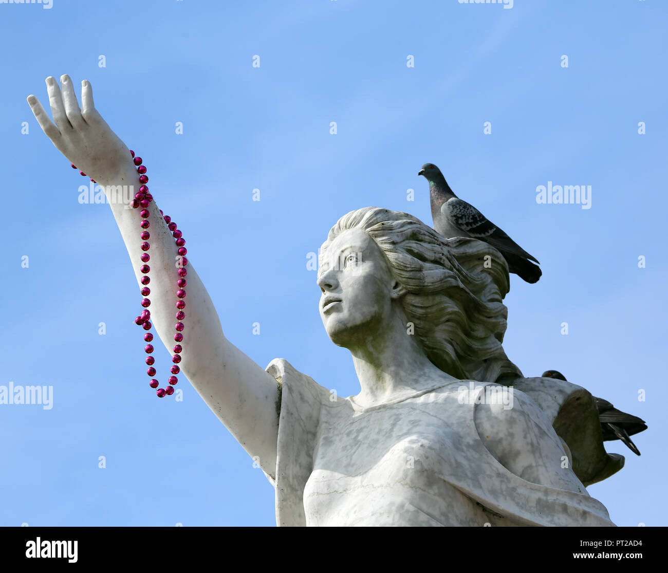 monument to immigration depicting woman with outstretched hand holding red beads and pigeon on head Stock Photo