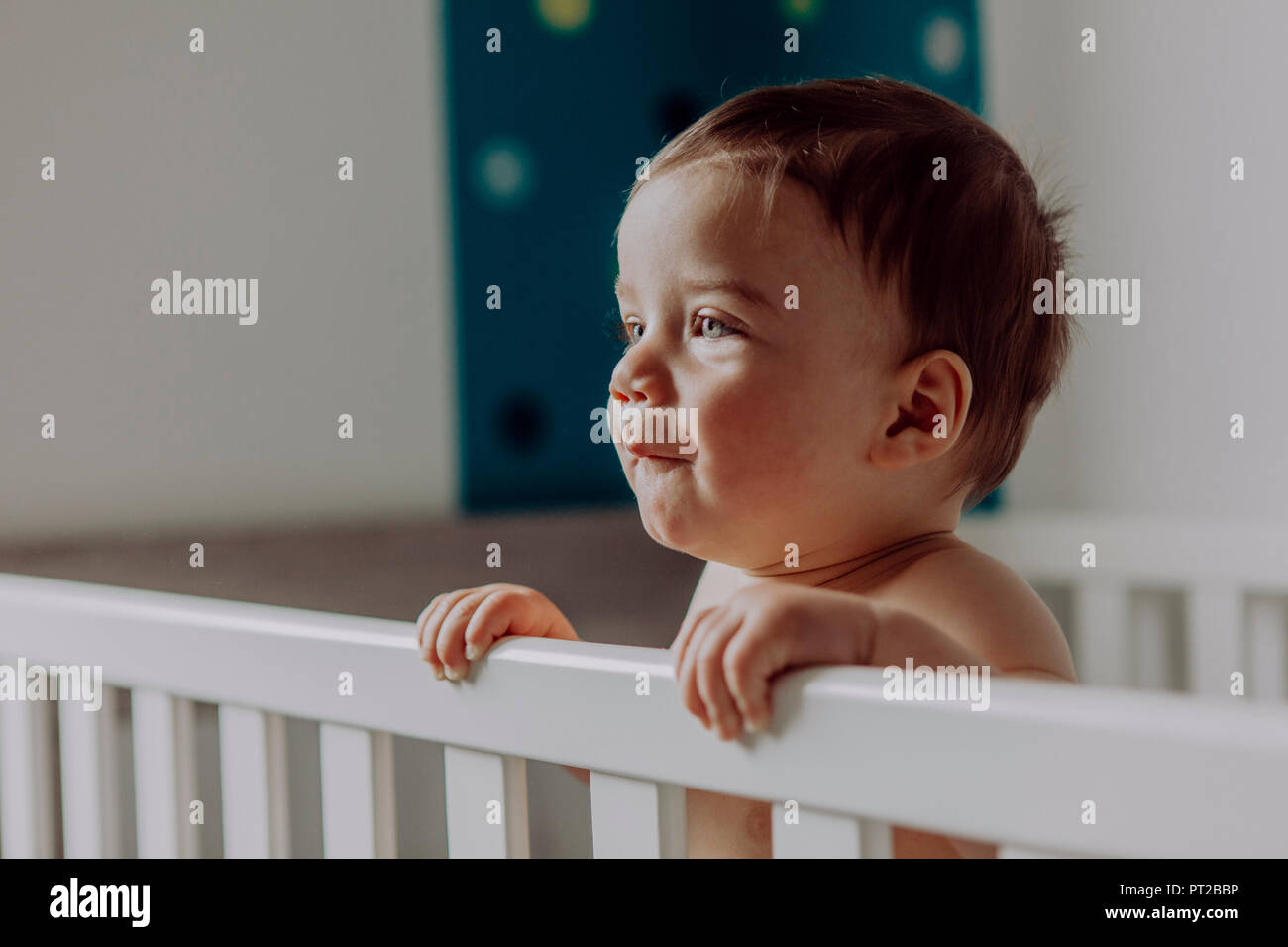 Baby boy standing in his cot Stock Photo