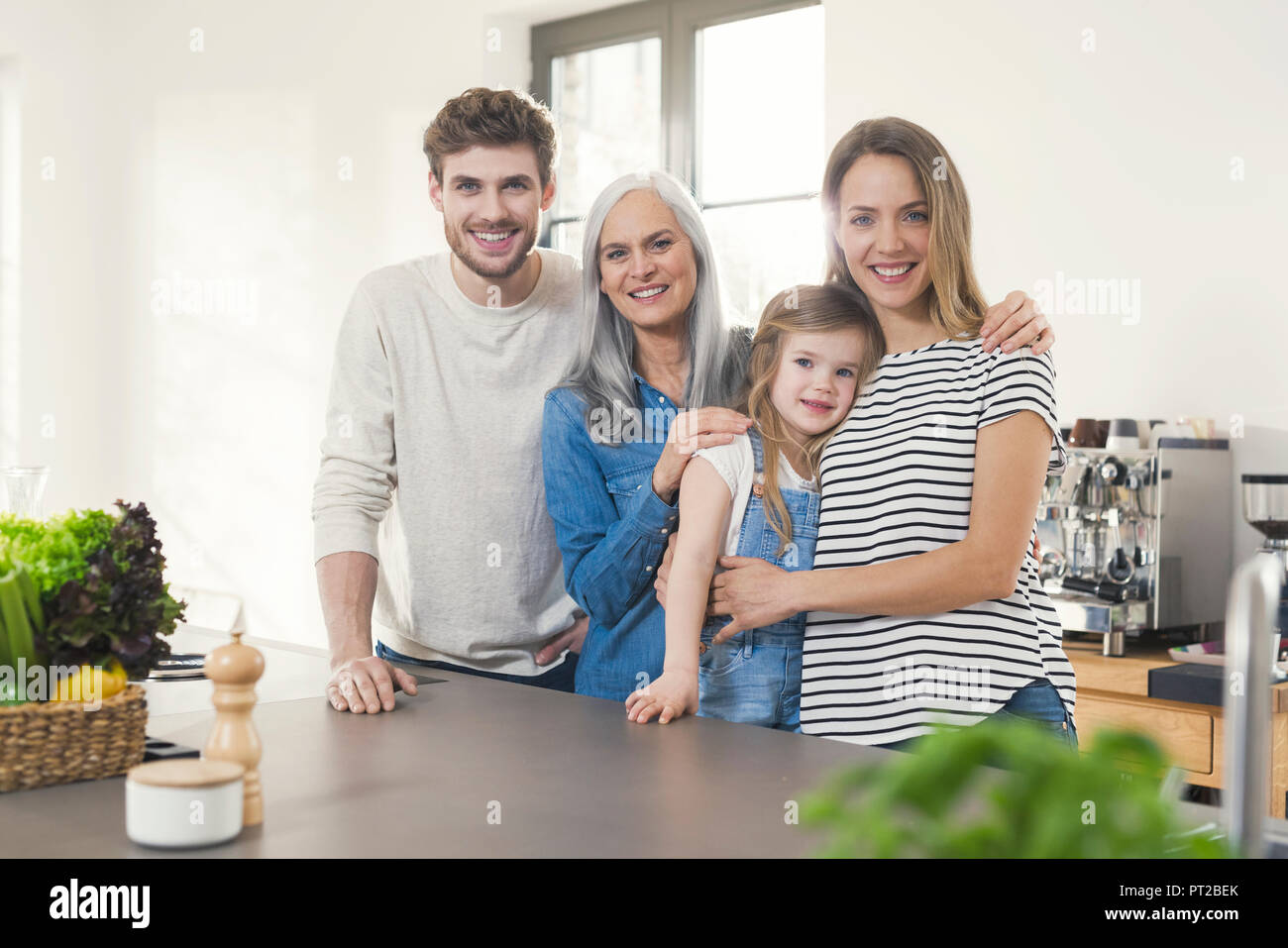 Happy three generations family standing in kitchen Stock Photo