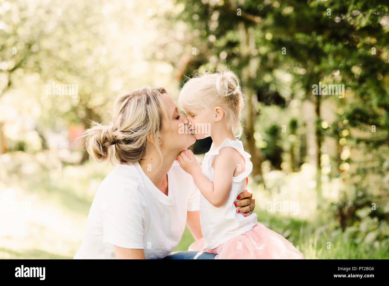 Happy mother kissing her little daughter outdoors Stock Photo