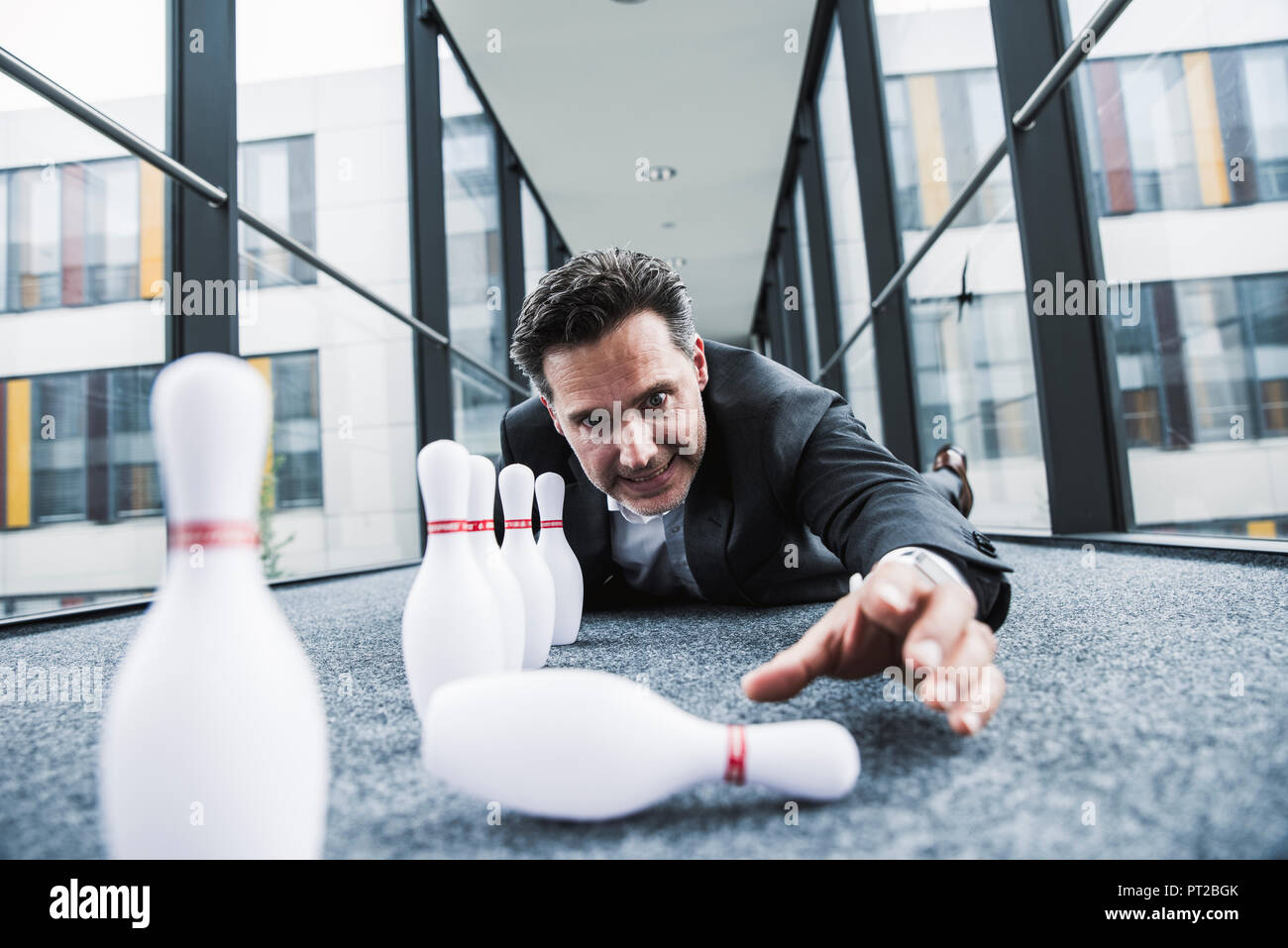 Obsessive manager lying on the floor in office passageway with pins Stock Photo