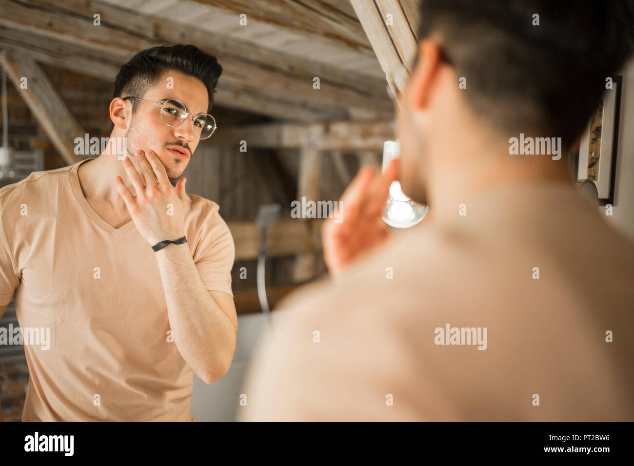 Young man looking in bathroom mirror Stock Photo