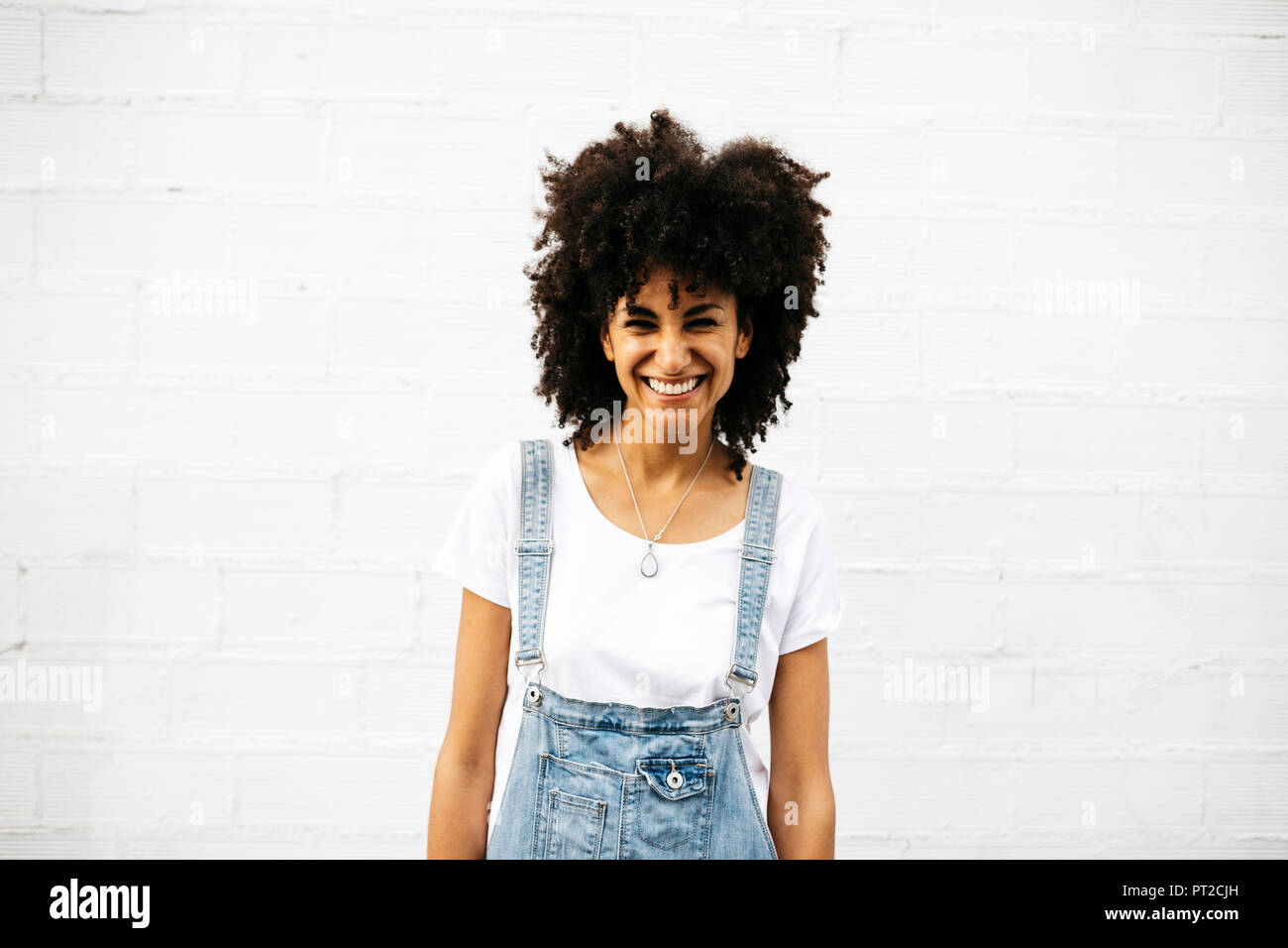 Portrait of laughing woman in front of white wall Stock Photo - Alamy