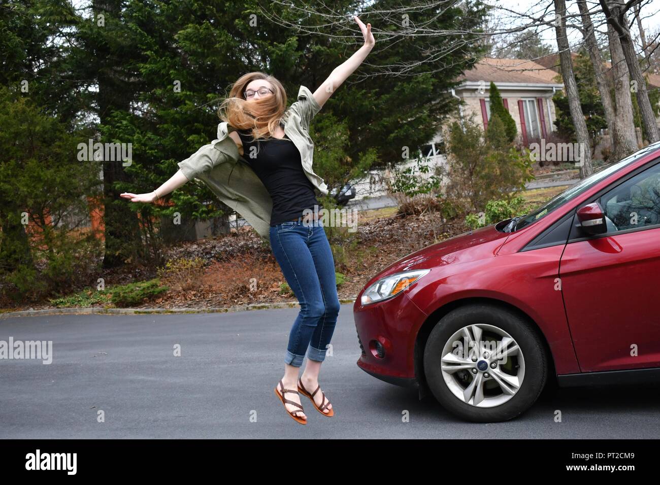 happy blond girl jumping for joy by new car Stock Photo - Alamy
