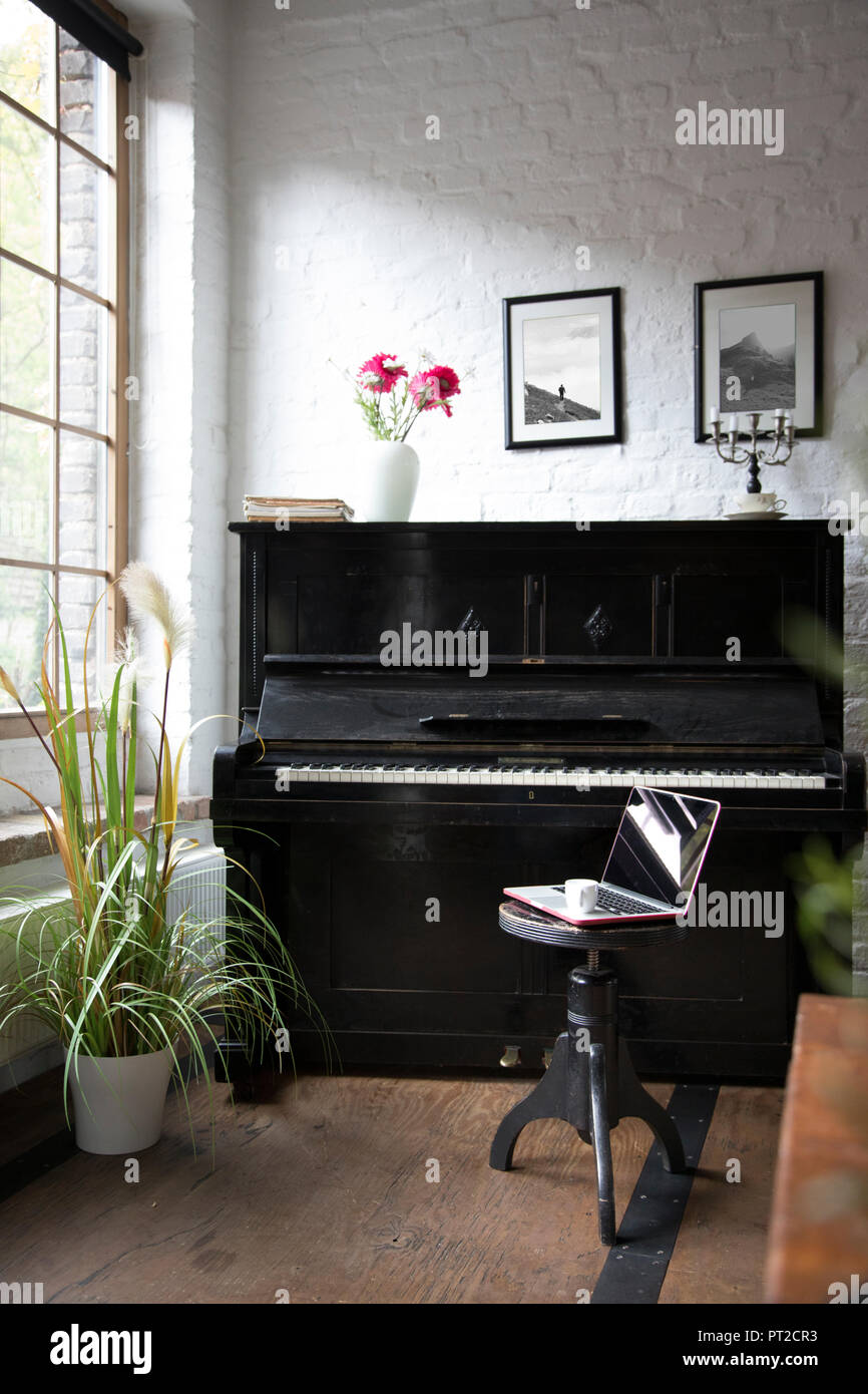 Piano with laptop on a stool in comfortable loft apartment Stock Photo