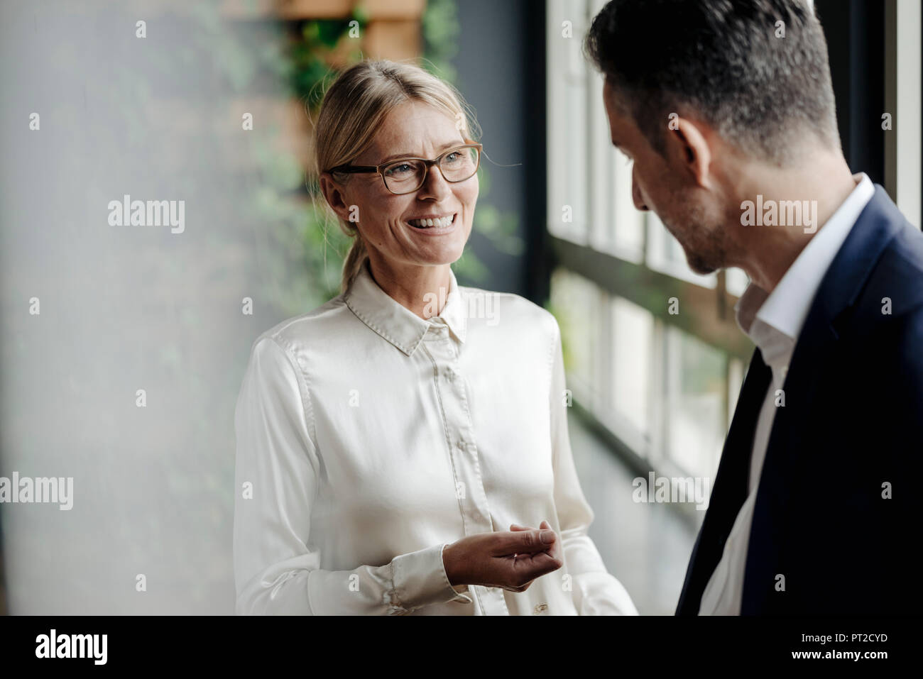 Businessman and businesswoman talking at the window Stock Photo