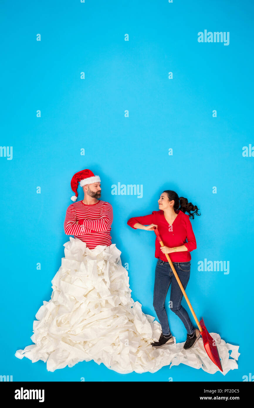Couple shoveling snow, man wearing Santa hat Stock Photo