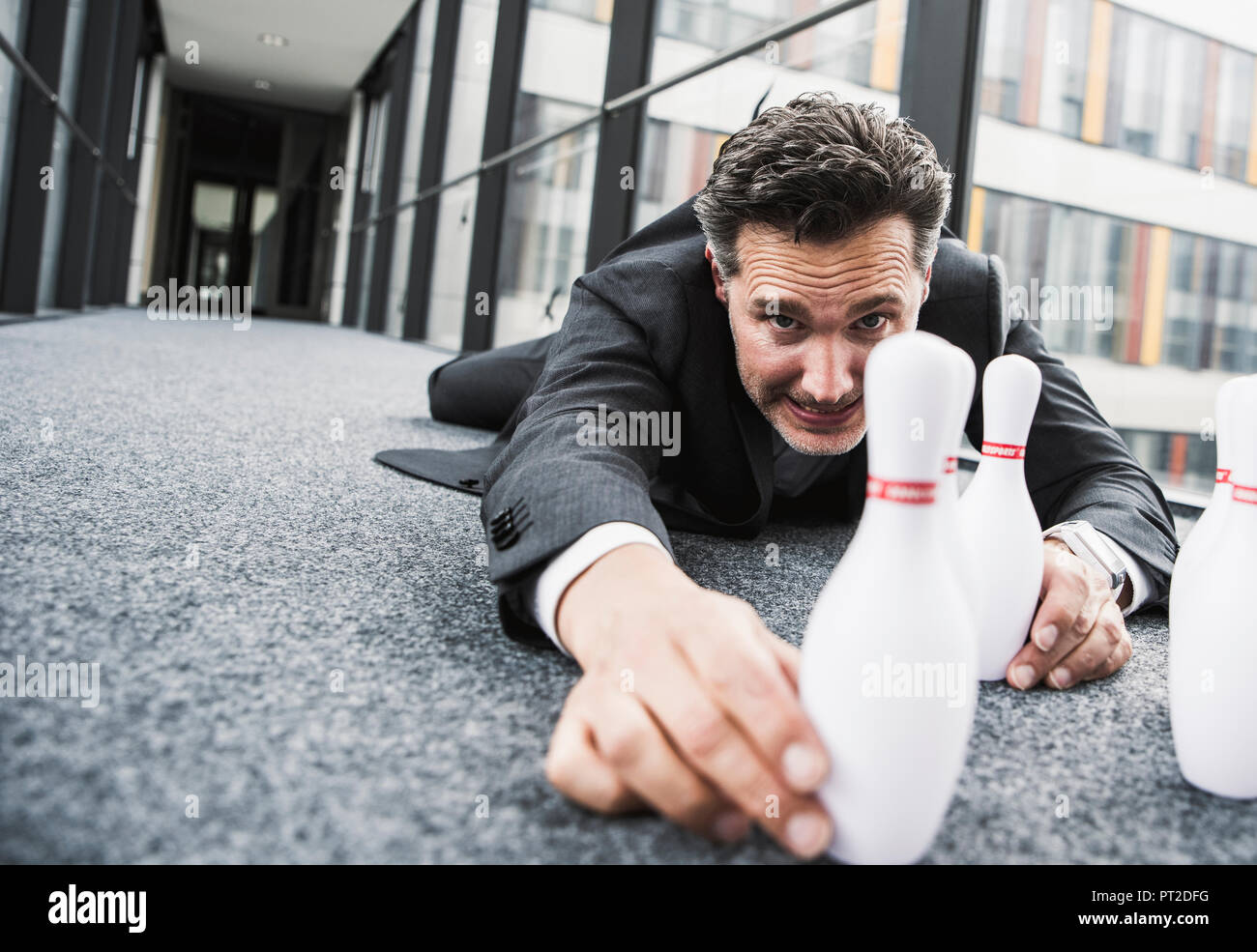 Obsessive manager lying on the floor in office passageway adjusting pins Stock Photo