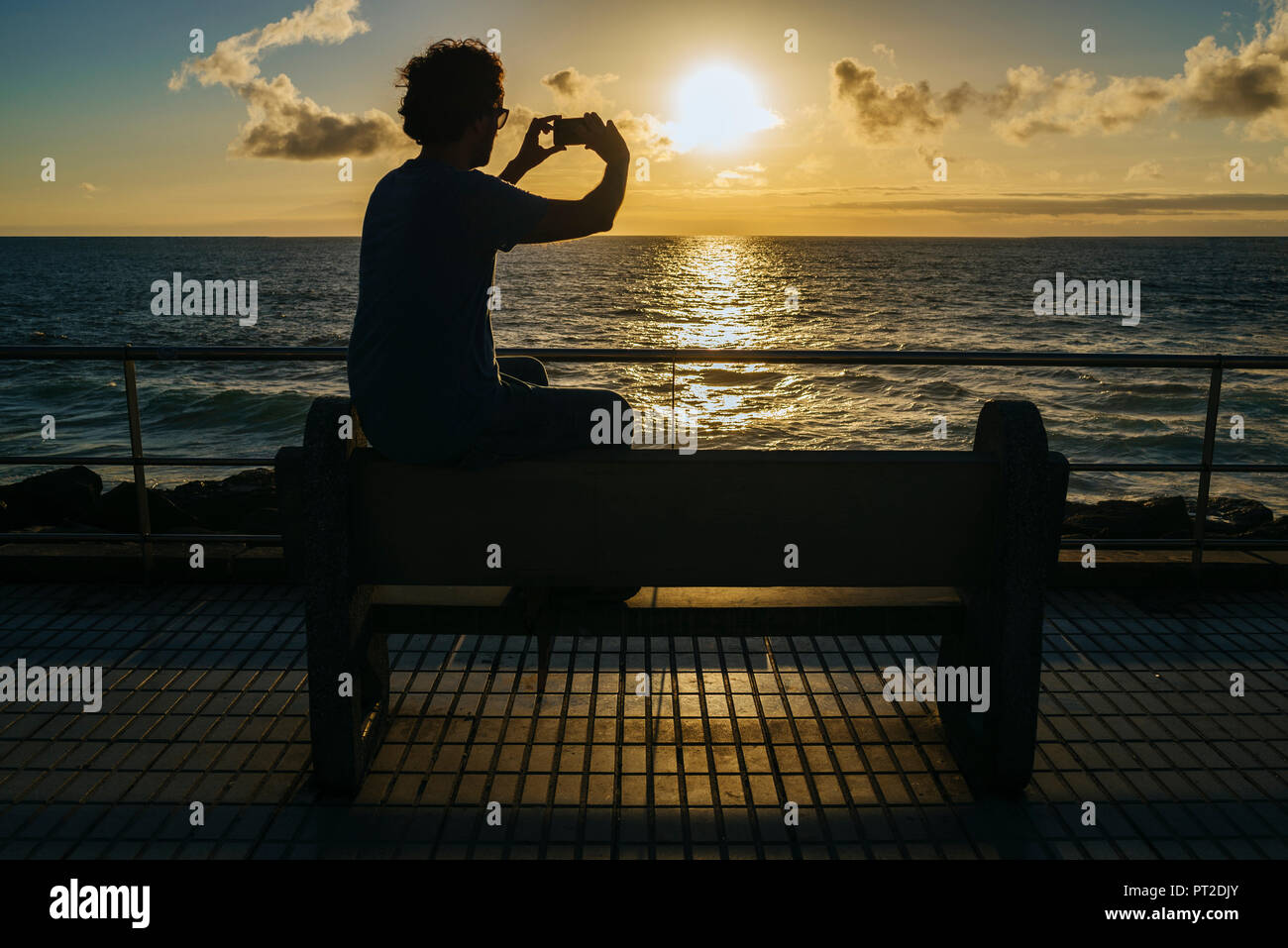 Spain, Canary Islands, Gran Canaria, Man taking a photo with mobile phone at sunset Stock Photo
