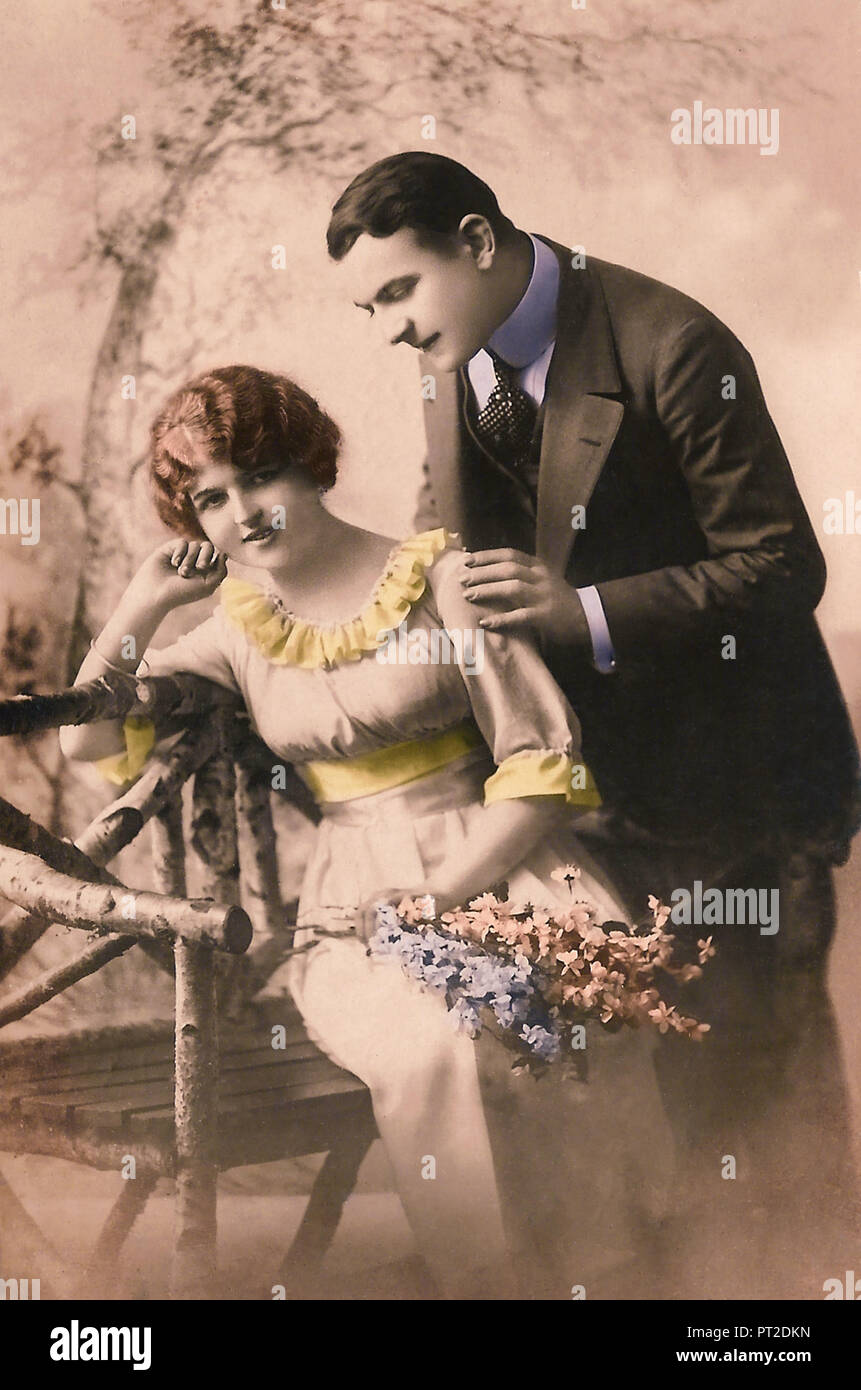 Vintage postcard of a couple in a garden. 1910s. Stock Photo