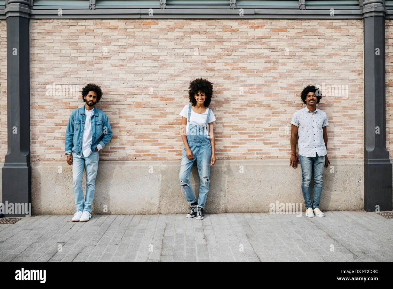Three Friends Standing In Front Of Brick Wall Stock Photo Alamy