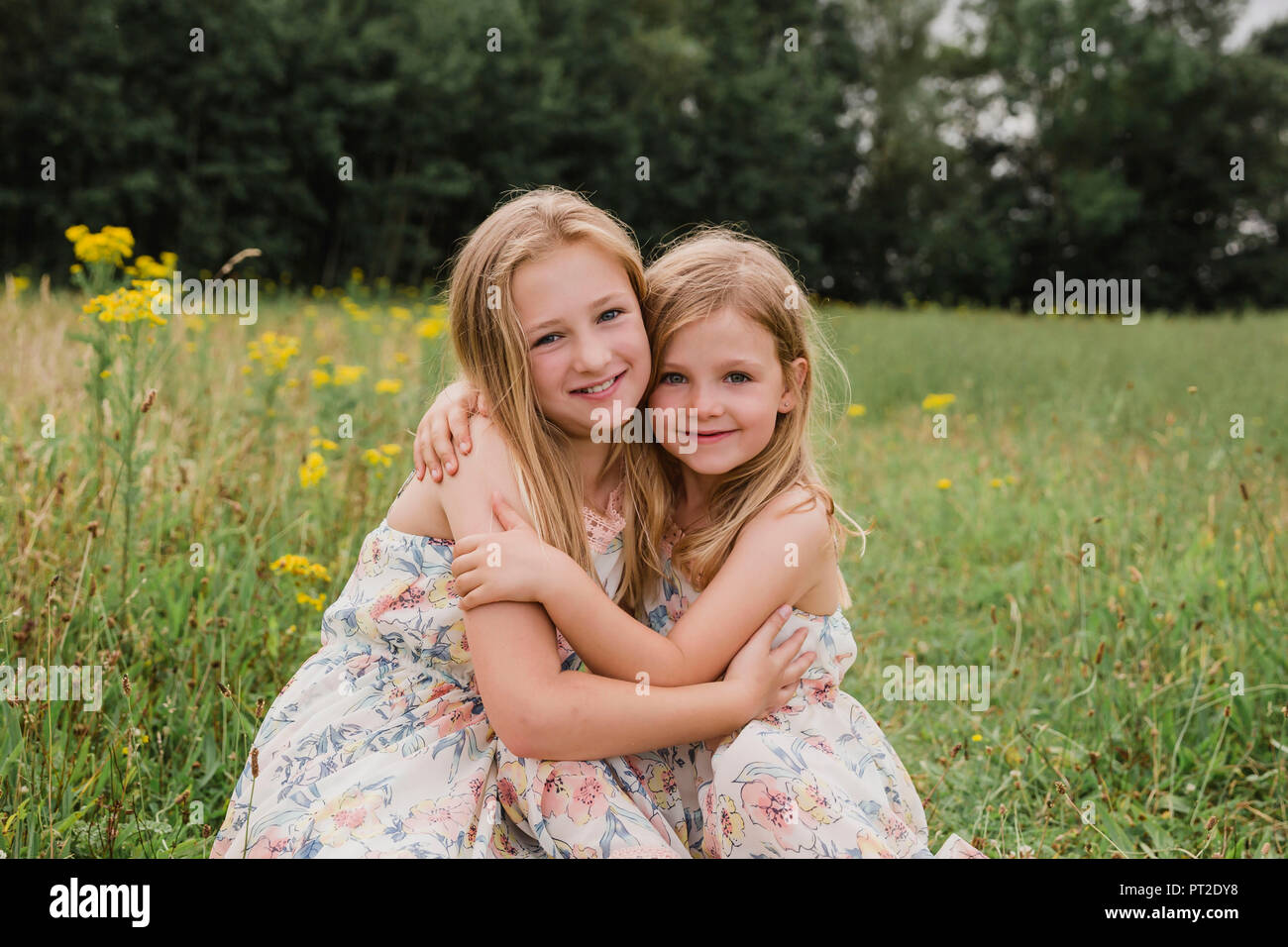 Two little sisters hugging each other on a meadow Stock Photo