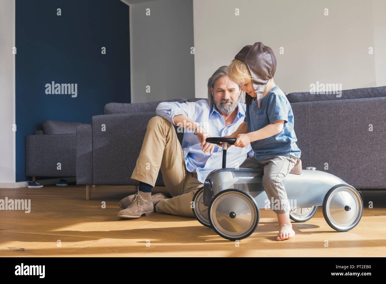 Grandfather playing with grandson, sitting on toy car Stock Photo