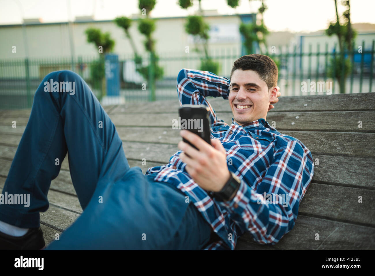 Young man lying and texting with his smartphone Stock Photo