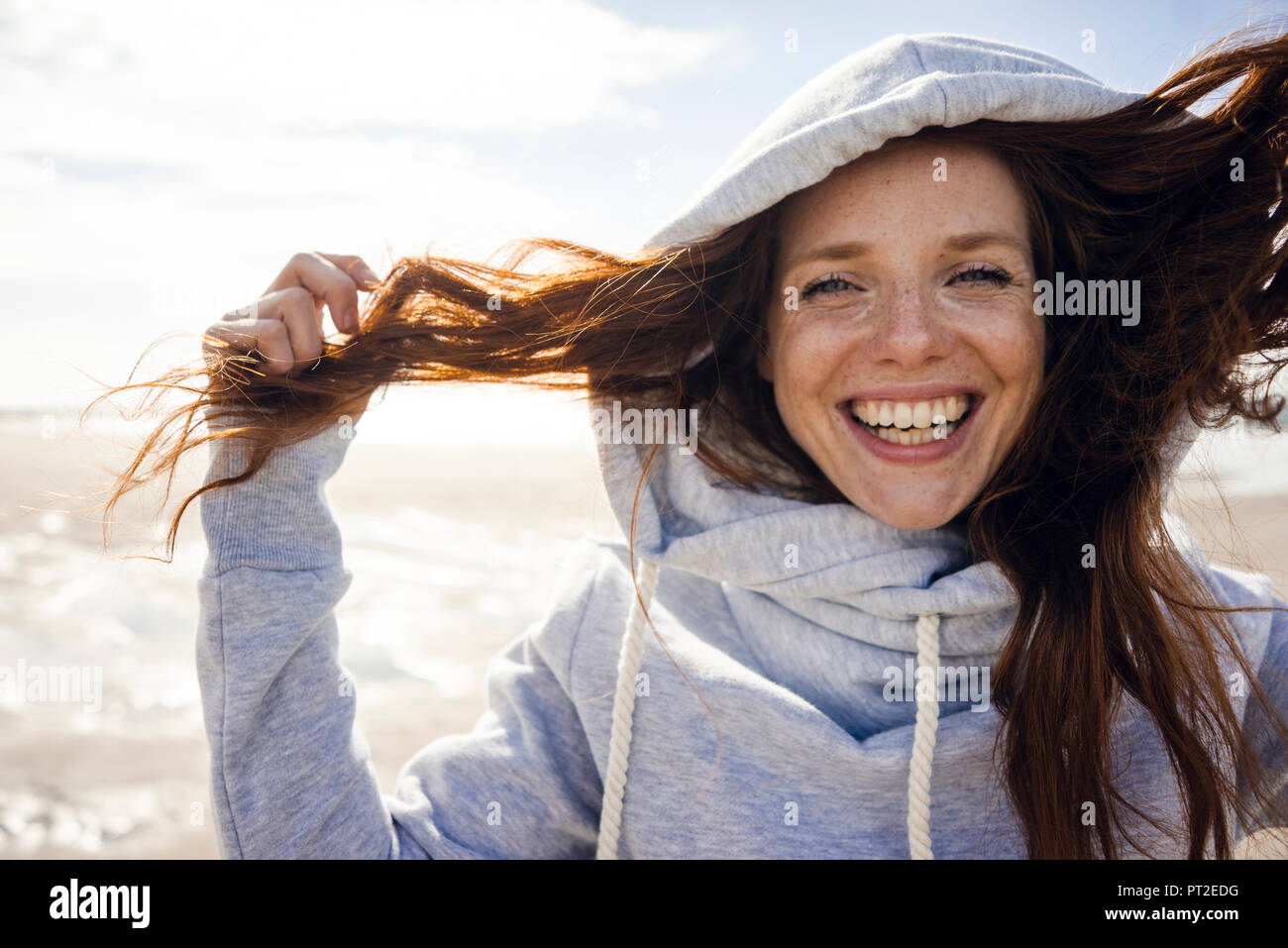 Woman having fun on a windy beach, wearing hood Stock Photo