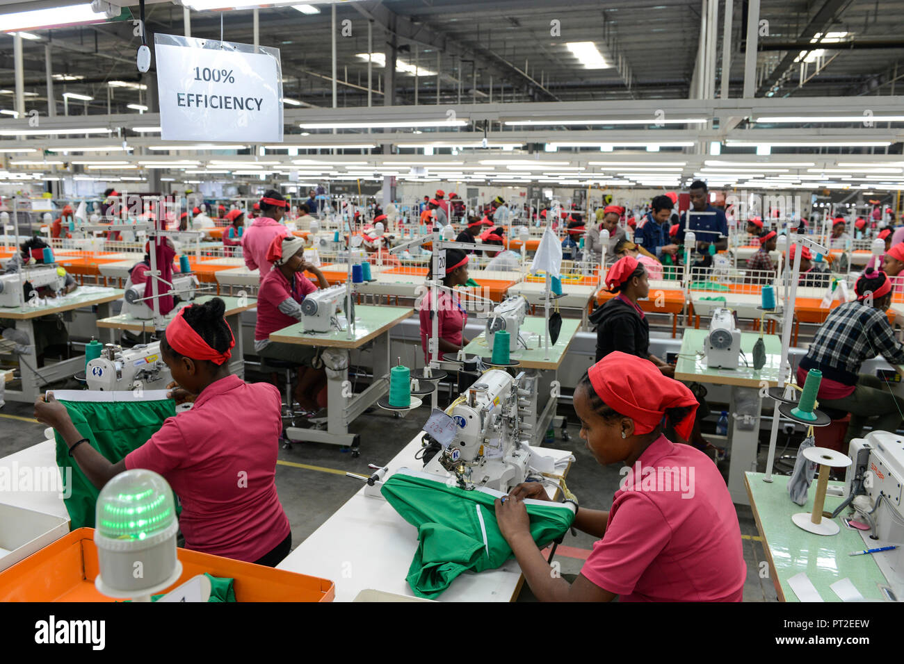 ETHIOPIA , Southern Nations, Hawassa or Awasa, Hawassa Industrial Park, chinese-built for the ethiopian government to attract foreign investors with low rent and tax free to establish a textile industry and create thousands of new jobs, taiwanese company Everest Textile Co. Ltd.produces textiles from synthetic fabric for export, women worker at sewing machine in production line, signboard 100% efficiency to stimulate improve of performance of the employees Stock Photo